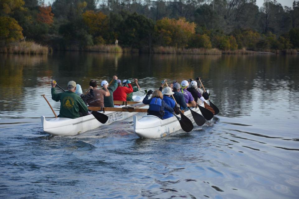 group learning how to paddle on lake natoma in an outrigger canoe